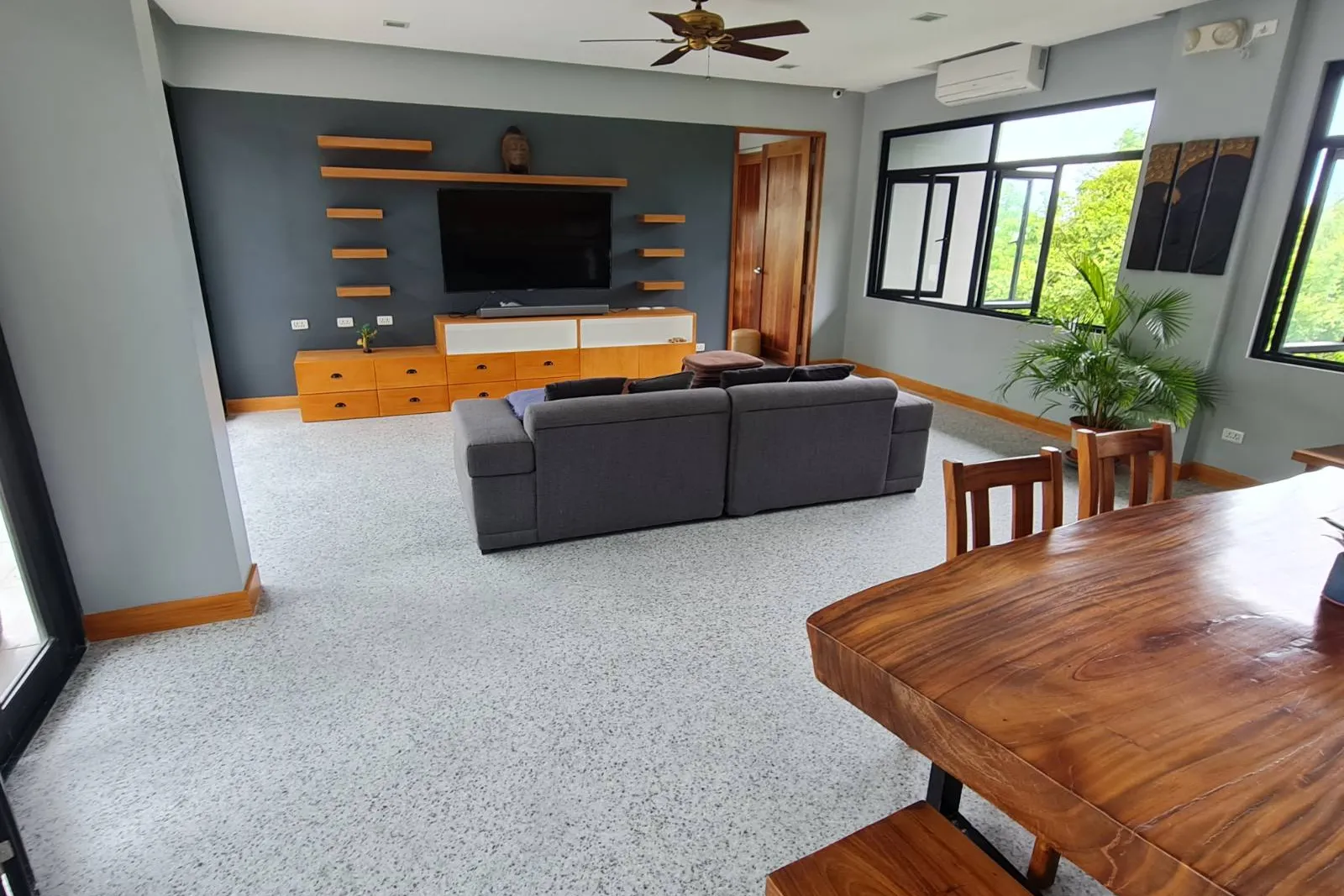 Living room with a light gray flake floor coating, a gray sofa and a wood dining table