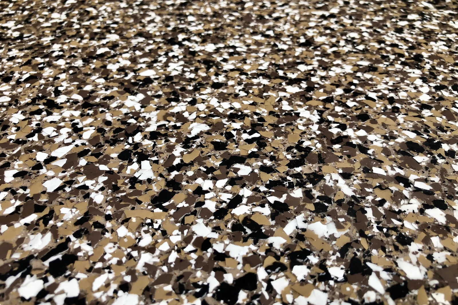 Close-up of tan, black and white flake floor coating