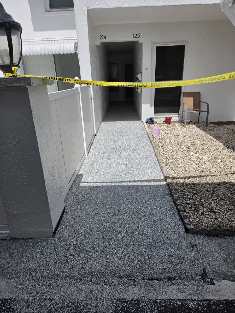Finished flake coating at a condo entry walkway in Pinellas County, cut clean at the step and gravel bed