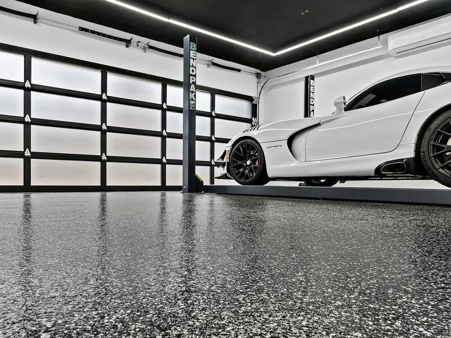 Gray flake floor coating in a garage with a sports car on a lift
