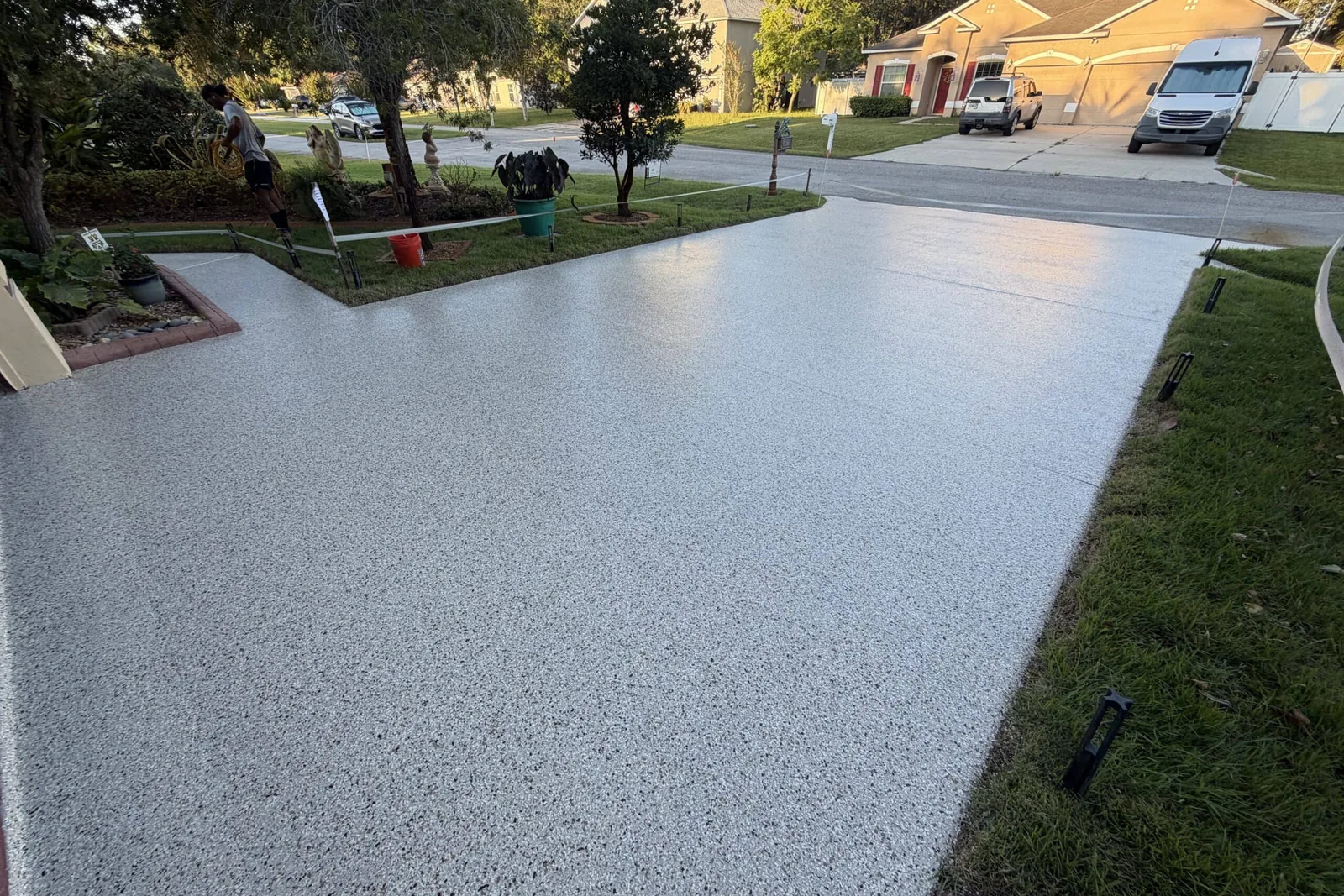 Gray flake coating on a residential driveway beside a lawn