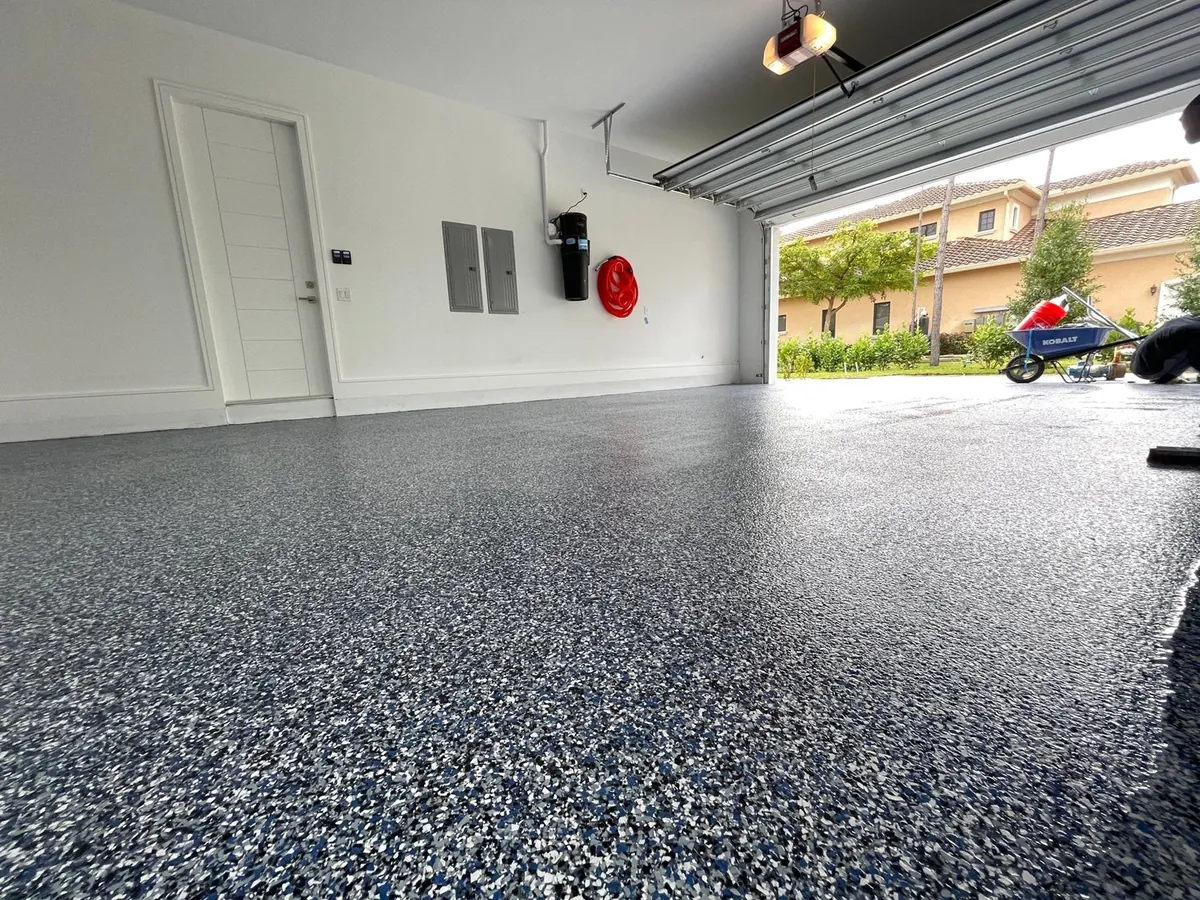 Garage with a gray and blue flake floor coating, the garage door open to the street